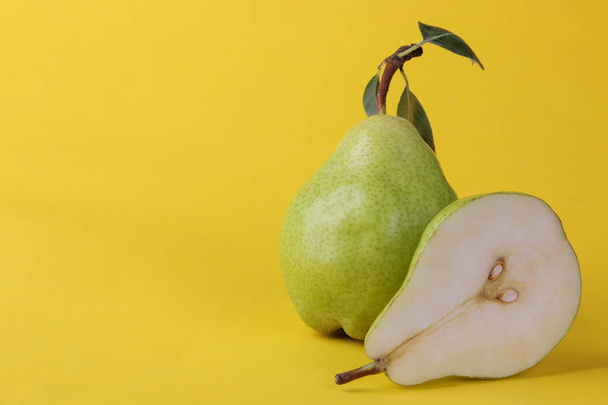 A fresh ripe pear and half a green pear on a bright yellow background with a place for an inscription - Photo, image