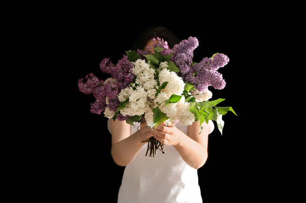 Mujer sosteniendo hermosa flor lila sobre fondo oscuro
 - Foto, Imagen