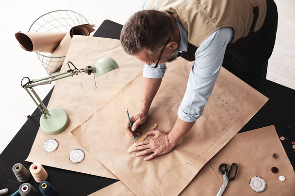 Sastre maduro trabajando con patrón de costura en atelier
 - Foto, Imagen
