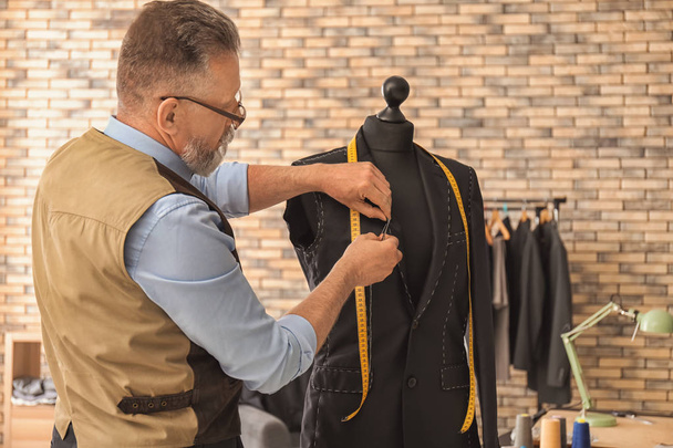 Seamster tailoring jacket on mannequin in atelier - Фото, зображення