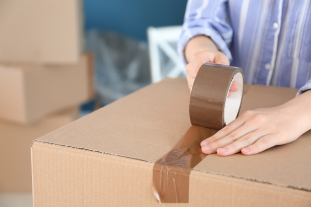 Woman packing carton box indoors. Moving house concept - Foto, Bild