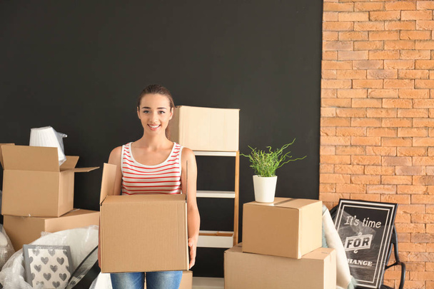 Young woman with box indoors. Moving into new house - Photo, Image