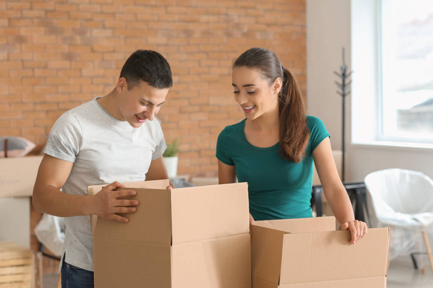 Young couple with boxes indoors. Moving into new house - Photo, Image