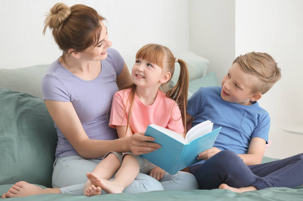 Moeder en haar kinderen lezen boek samen thuis - Foto, afbeelding