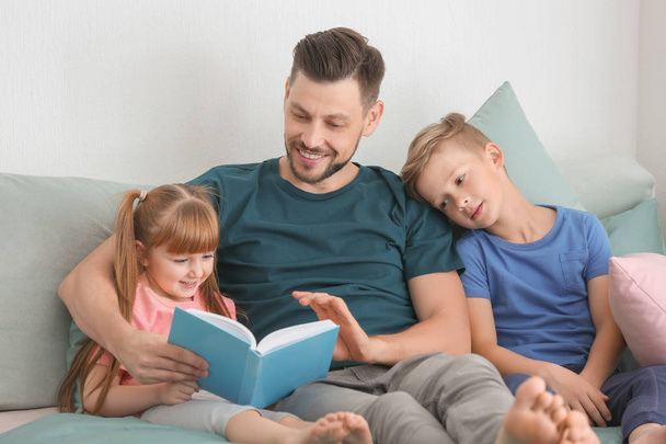 Pai e seus filhos lendo livro juntos em casa
 - Foto, Imagem