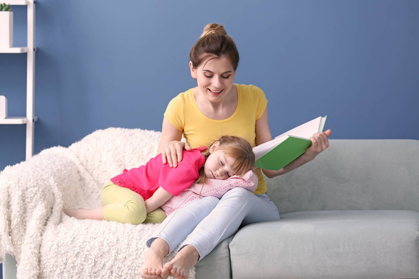Mother and her daughter reading book together at home - Фото, зображення