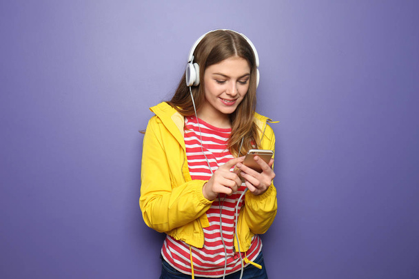 Beautiful young woman listening to music on color background - 写真・画像