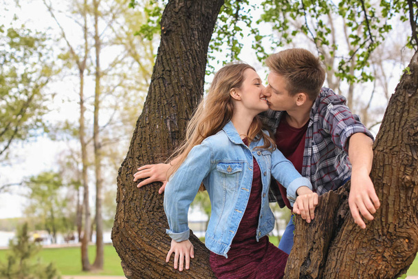 Šťastný mladý pár poblíž stromu v parku na jarní den - Fotografie, Obrázek