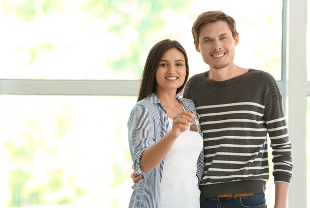 Young happy couple with key of their new house indoors - 写真・画像