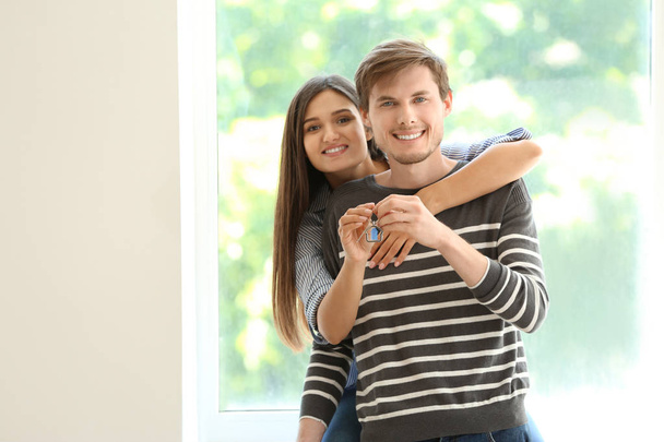 Jovem casal feliz com a chave de sua nova casa dentro de casa
 - Foto, Imagem