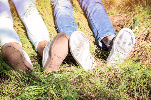 Legs of young couple lying on green grass in park - Photo, Image