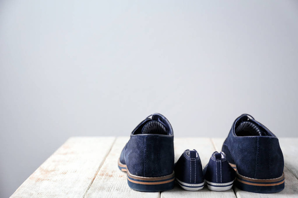 Big and small shoes on wooden table against light background. Father's day - Foto, Imagem