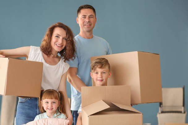 Gelukkige familie met kartonnen dozen binnenshuis. Verhuizen naar nieuw huis - Foto, afbeelding