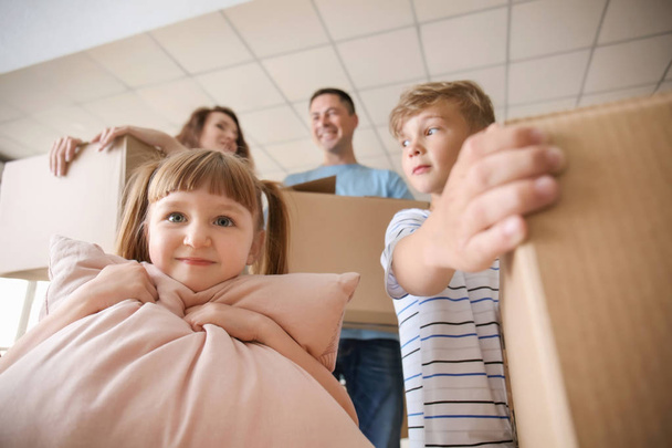 I bambini e i loro genitori con scatole al chiuso. Trasferirsi in una nuova casa
 - Foto, immagini