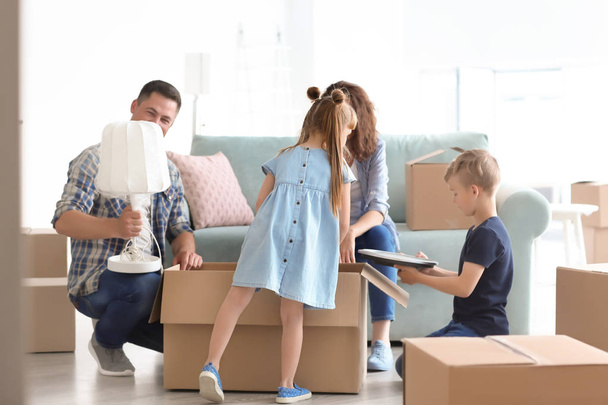 Счастливая семья распаковывает коробки в помещении. Переезд в новый дом
 - Фото, изображение