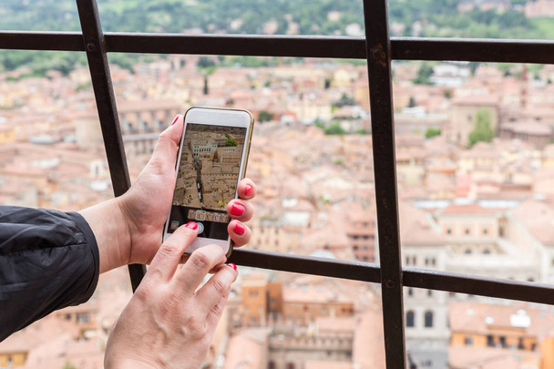 Turista de mano sosteniendo el teléfono inteligente tomando una foto de Bolonia Italia
 - Foto, Imagen