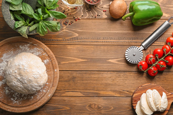 Raw dough and ingredients for pizza on wooden background - Фото, зображення