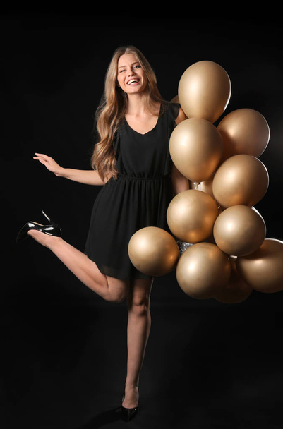 Όμορφη νεαρή γυναίκα με μπαλόνια σε σκούρο φόντο - Φωτογραφία, εικόνα