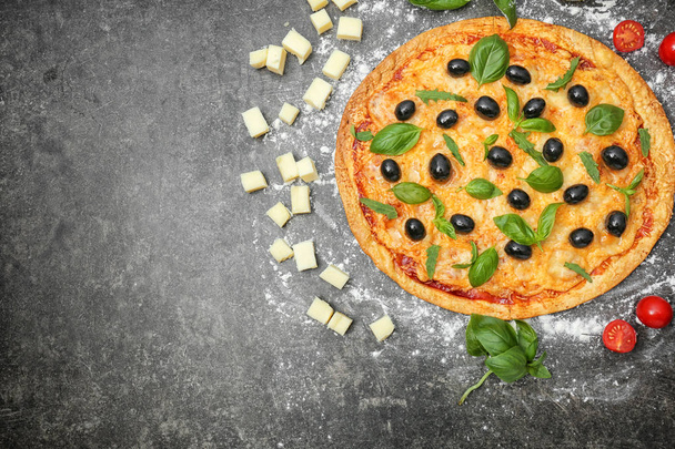 Tasty pizza with olives and ingredients on dark background - Photo, Image