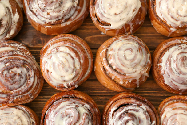 Tasty homemade cinnamon buns with glaze on wooden table, top view - Photo, Image