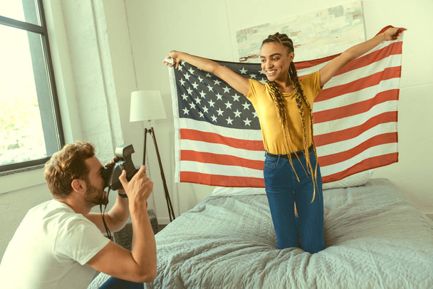 Excited girlfriend posing with american flag t home - Фото, изображение