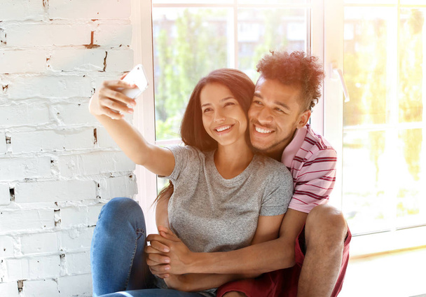 Feliz pareja afroamericana tomando selfie en casa
 - Foto, imagen