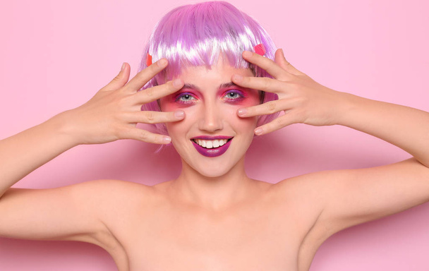 Mujer joven con cabello inusual y maquillaje profesional sobre fondo de color
 - Foto, Imagen