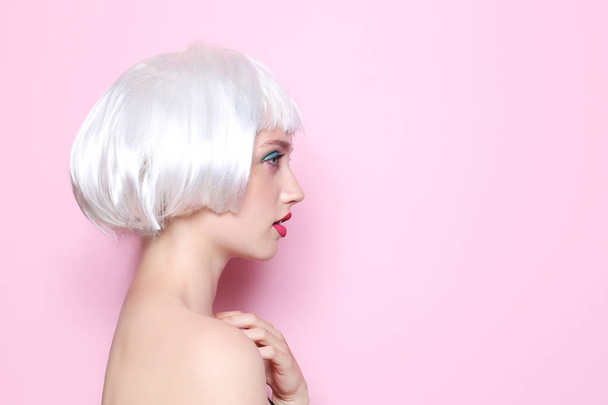 Young woman with wig and professional makeup on color background - Foto, Imagem
