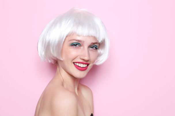 junge Frau mit Perücke und professionellem Make-up auf farbigem Hintergrund - Foto, Bild