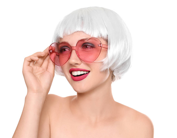 Young woman with wig and sunglasses on white background - Foto, Bild