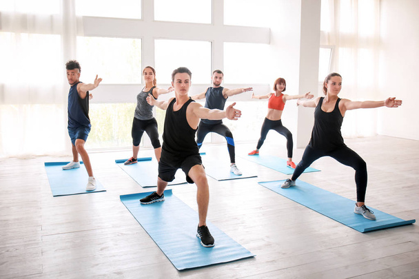 Группа спортсменов, практикующих йогу в помещении
 - Фото, изображение