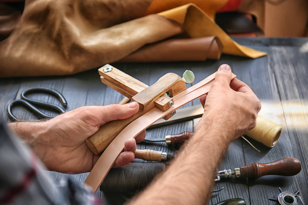 Homem usando braçadeira de costura enquanto trabalhava com couro na fábrica, close-up
 - Foto, Imagem