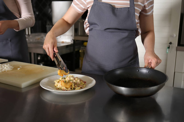 Jonge vrouw maaltijd bereiden tijdens kooklessen op restaurant keuken - Foto, afbeelding
