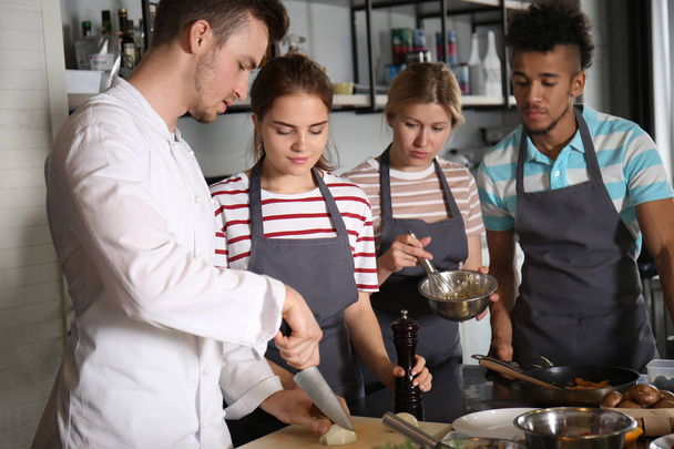 Шеф-повар и группа молодых людей во время кулинарных занятий
 - Фото, изображение