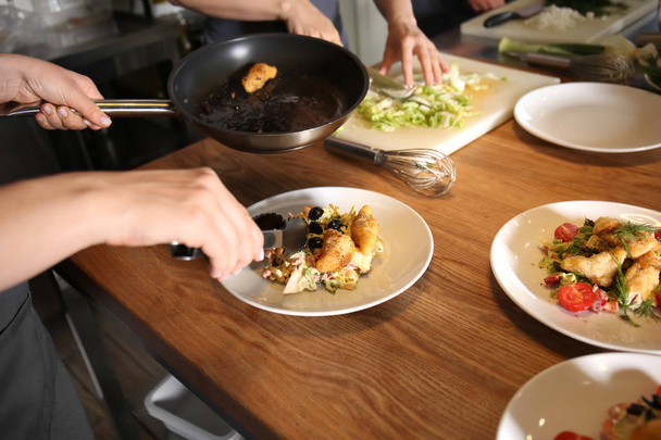 junge Frau bereitet bei Kochkursen in Restaurantküche schmackhaftes Fleisch und Salat zu - Foto, Bild