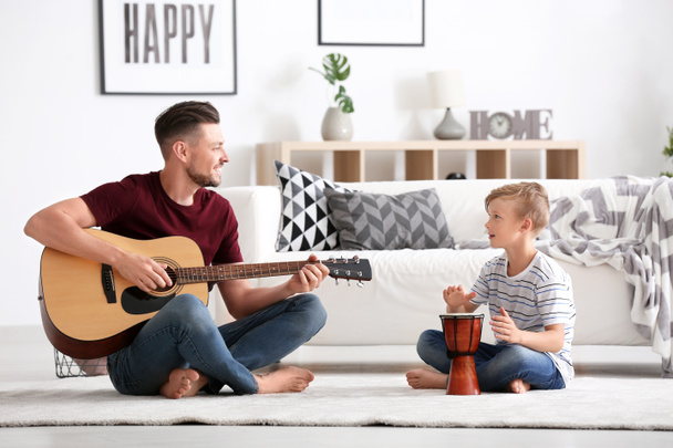 Μικρό αγόρι και ο μπαμπάς του με μουσικά όργανα παίζουν στο σπίτι - Φωτογραφία, εικόνα