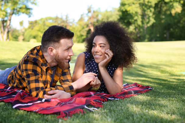 junges liebevolles gemischtrassiges Paar ruht sich an einem Frühlingstag im Park aus - Foto, Bild
