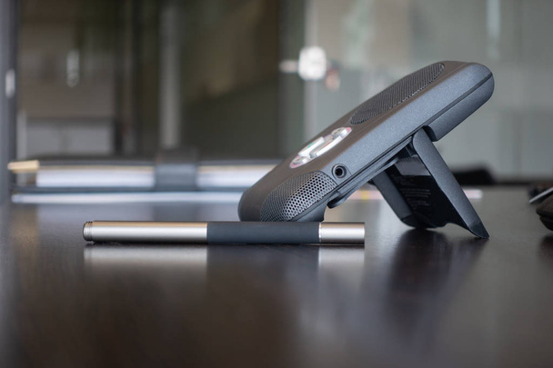 Dispositivo de comunicação sem fio, voz sobre o telefone da internet na mesa de escritório limpa, marrom escuro, caneta stylus na mesa e portfólio de pasta de negócios clássico em segundo plano
 - Foto, Imagem
