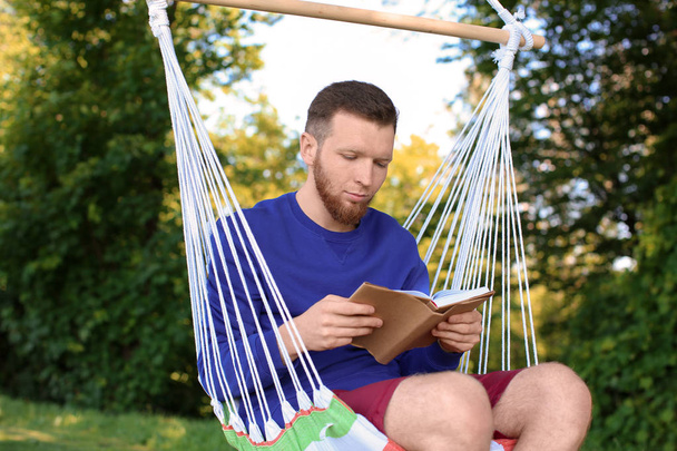 Młodego człowieka, czytanie książki w hamaku na zewnątrz - Zdjęcie, obraz