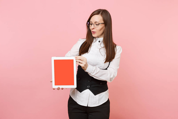 Молодая успешная деловая женщина в костюме и очках держит планшетный компьютер с пустым пустым экраном, изолированным на розовом фоне. Леди-босс. Достижение карьерного богатства. Копирование места для рекламы
 - Фото, изображение