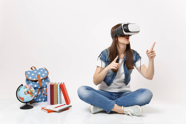 Молода здивована студентка у окулярах віртуальної реальності, вказуючи індекс пальців вгору поблизу глобуса, рюкзака, шкільних книг ізольовані на білому тлі. Освіта в школі концепція коледжу університету
 - Фото, зображення