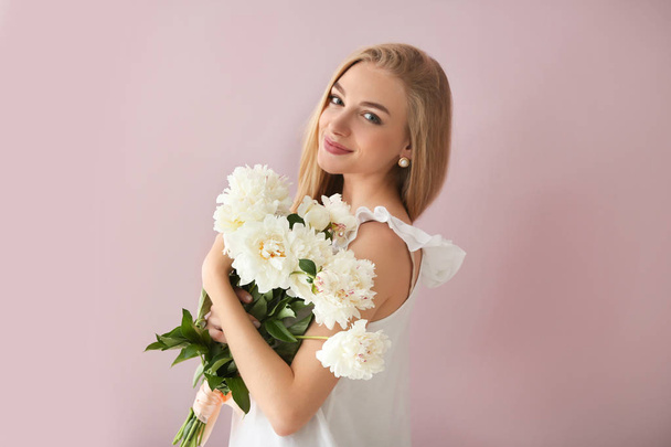 Attractive young woman with beautiful flowers on color background - Fotografie, Obrázek
