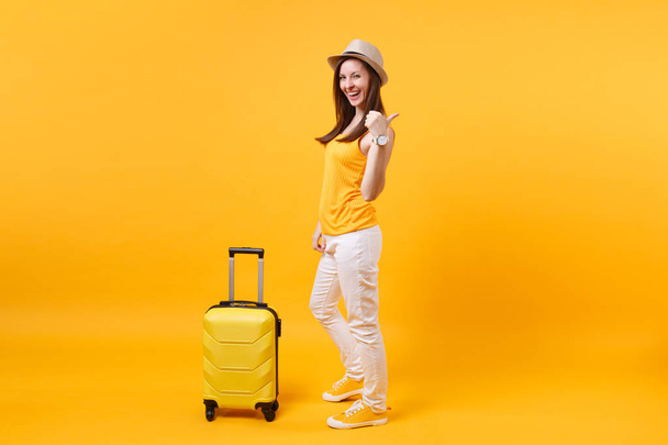Traveler tourist woman in summer casual clothes, hat with suitcase isolated on yellow orange background. Female passenger traveling abroad to travel on weekends getaway. Air flight journey concept - Foto, Bild