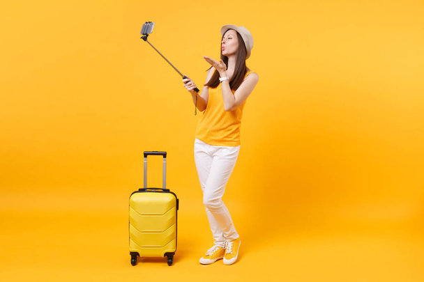 Mulher turística feliz no verão roupas casuais, chapéu fazendo tiro selfie no telefone celular isolado no fundo laranja amarelo. Passageiro viajando para o exterior para viajar nos fins de semana de fuga. Conceito de voo aéreo
 - Foto, Imagem
