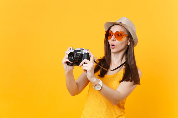 Toeristische vrouw in zomer casual kleding, hoed neem foto op retro vintage fotocamera geïsoleerd op gele achtergrond. Meisje reizen in het buitenland te reizen op weekend uitje. Air vlucht reis concept - Foto, afbeelding