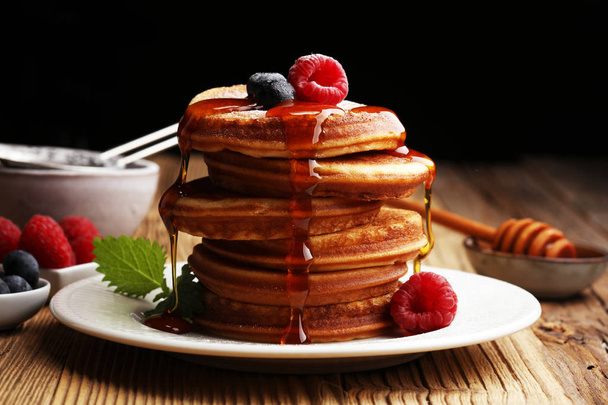 Pancakes with berries and maple syrup on rustic table. - Photo, Image