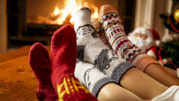 Closeup photo of female feet in warm woolen socks warming by the fireside at house - Photo, Image