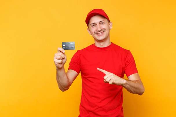 Παράδοση από τον άνθρωπο στην κόκκινη στολή απομονώνονται σε κίτρινο πορτοκαλί φόντο. Επαγγελματική χαμογελώντας αρσενικό υπάλληλος στην ΚΓΠ, κενό t-shirt courier ή έμπορος κράτημα στο χέρι πιστωτική κάρτα Τράπεζας. Έννοια υπηρεσιών. Χώρο αντίγραφο - Φωτογραφία, εικόνα