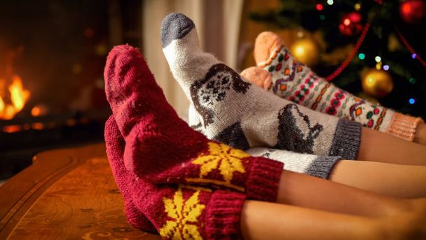 Closeup photo of family feet in warm socks lying next to Christmas tree and burning fireplace - Photo, Image