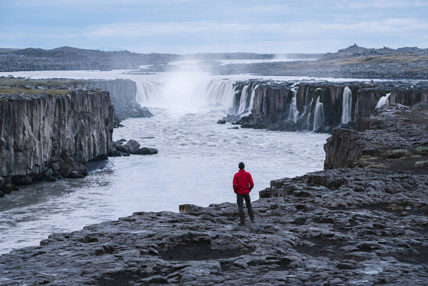 Selfoss водоспад. Хлопець у Червоний жакет дивиться на Каскад води. Знаменитий туристичною визначною пам'яткою Ісландії. Красу в природі - Фото, зображення